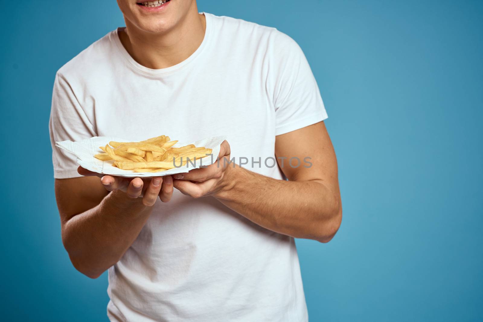 man with fries in cardboard plate calories fast food blue background teen model cropped view by SHOTPRIME