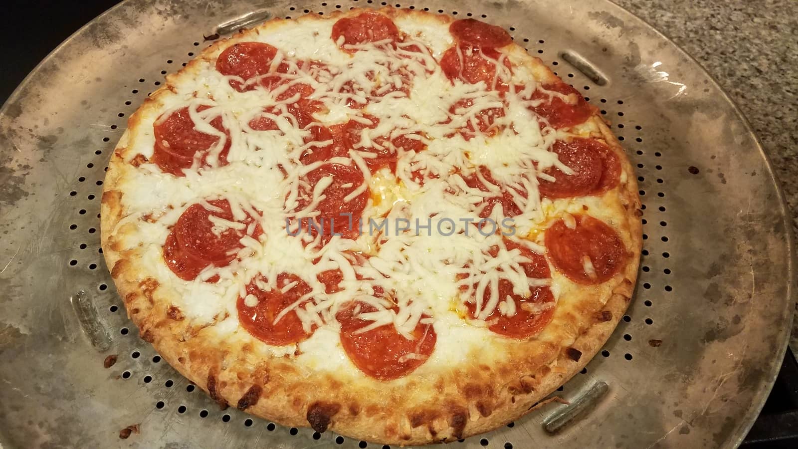 pepperoni pizza with cheese and grease on metal baking tray