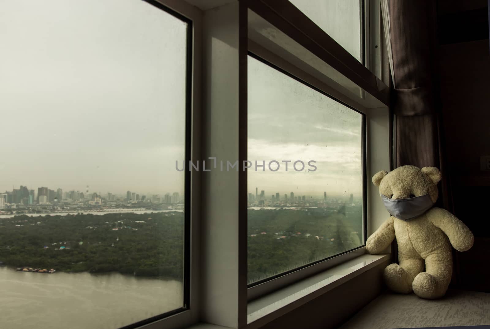 Sad teddy bear in protective medical masks sits on windowsill and looks out window. Stay at home quarantine coronavirus pandemic prevention, Virus outbreak in a world. No focus, specifically.