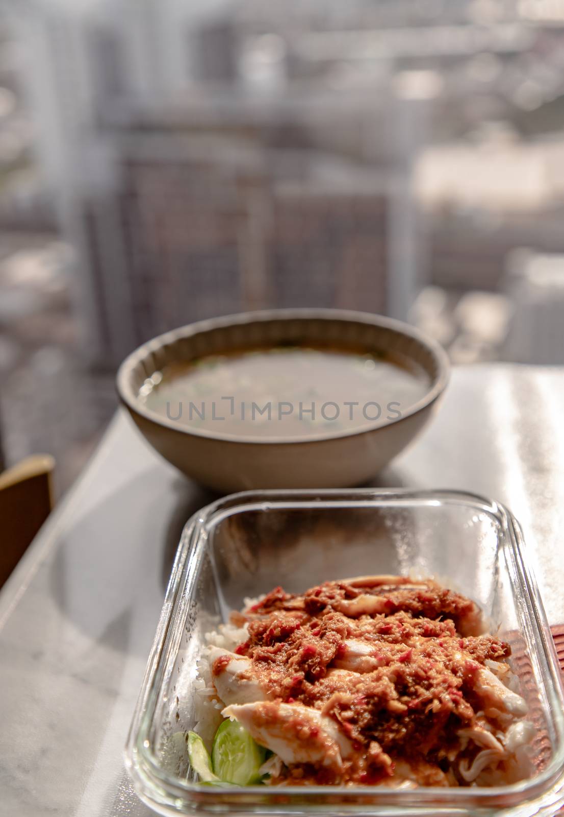 Chicken rice with Chicken broth over marble table at morning. Selective focus.