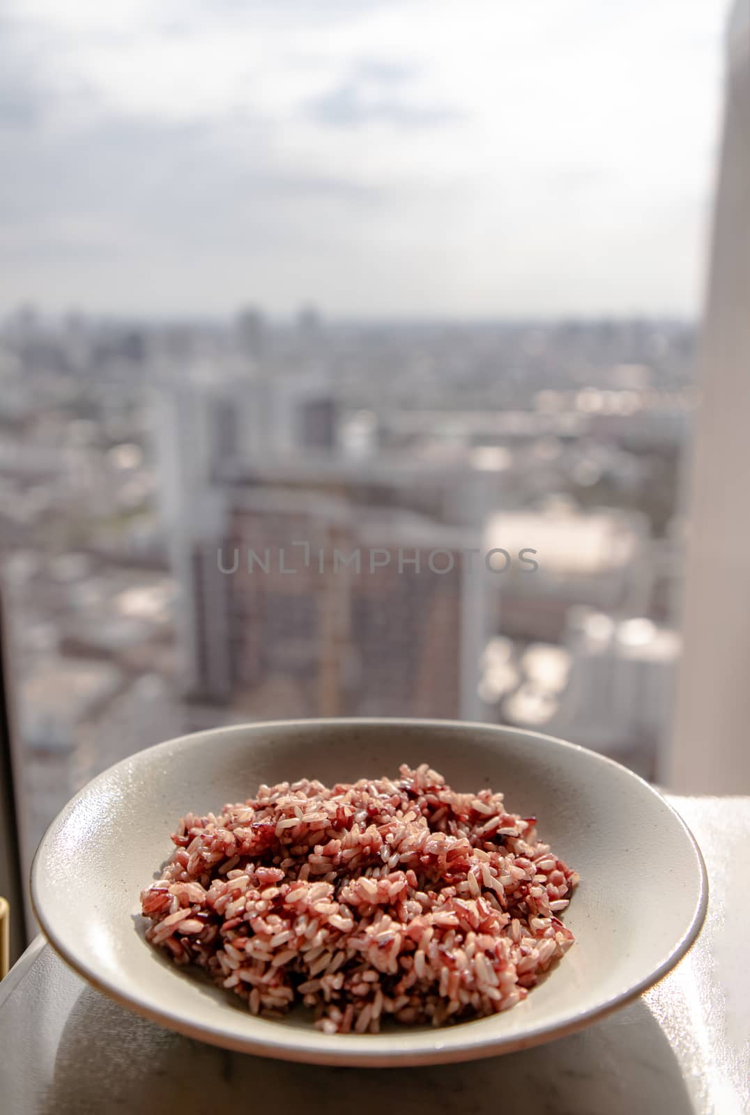 Riceberry in white dish over white table with city view at morning. Selective focus.