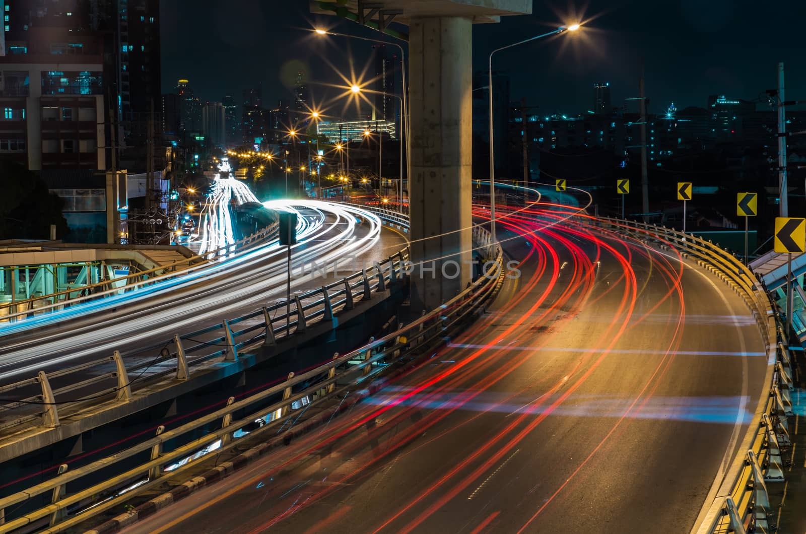 Overpass of the light trails with Bangkok city background at night. Beautiful curves. Selective focus.