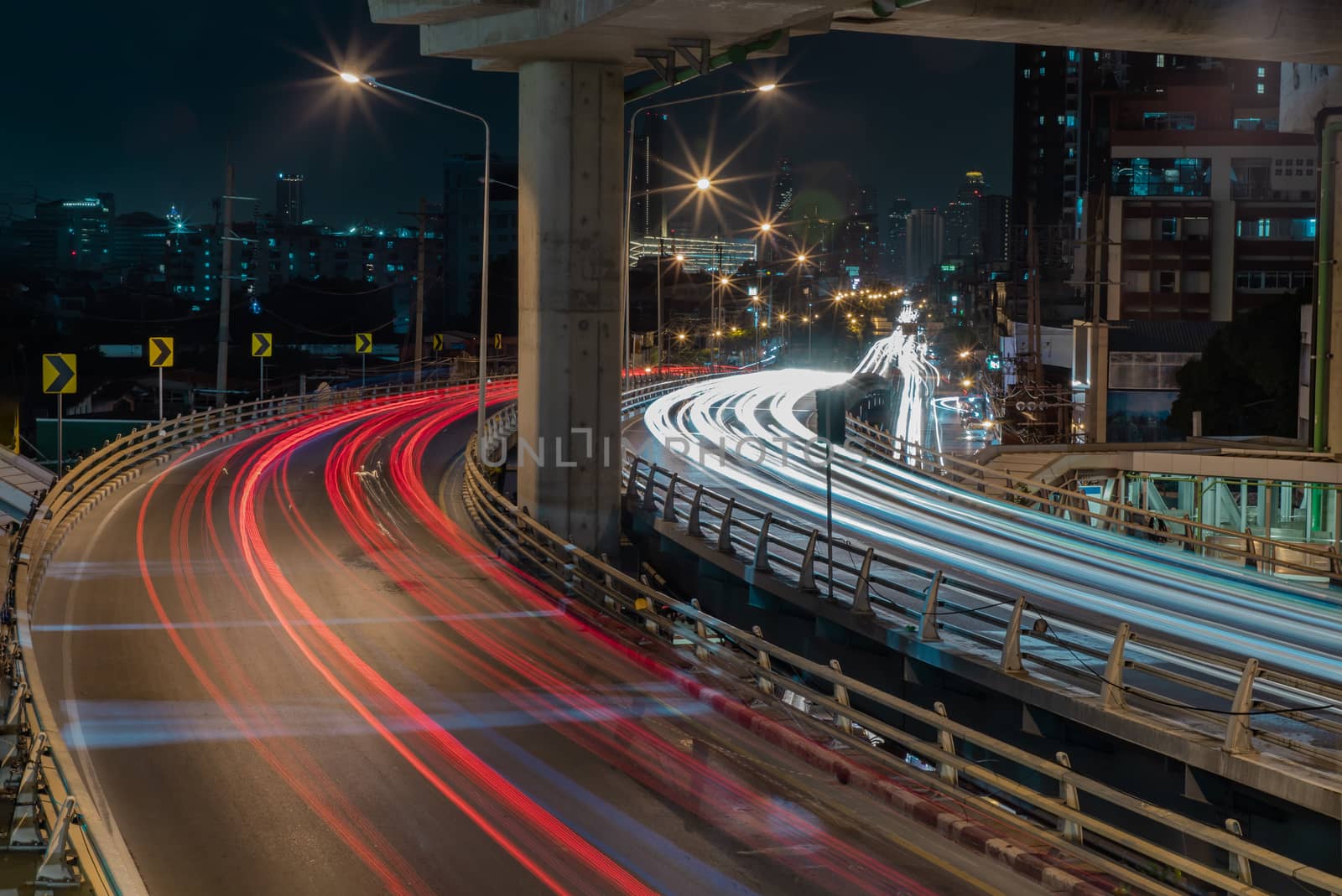 Overpass of the light trails with Bangkok city background at night. Beautiful curves. Selective focus.