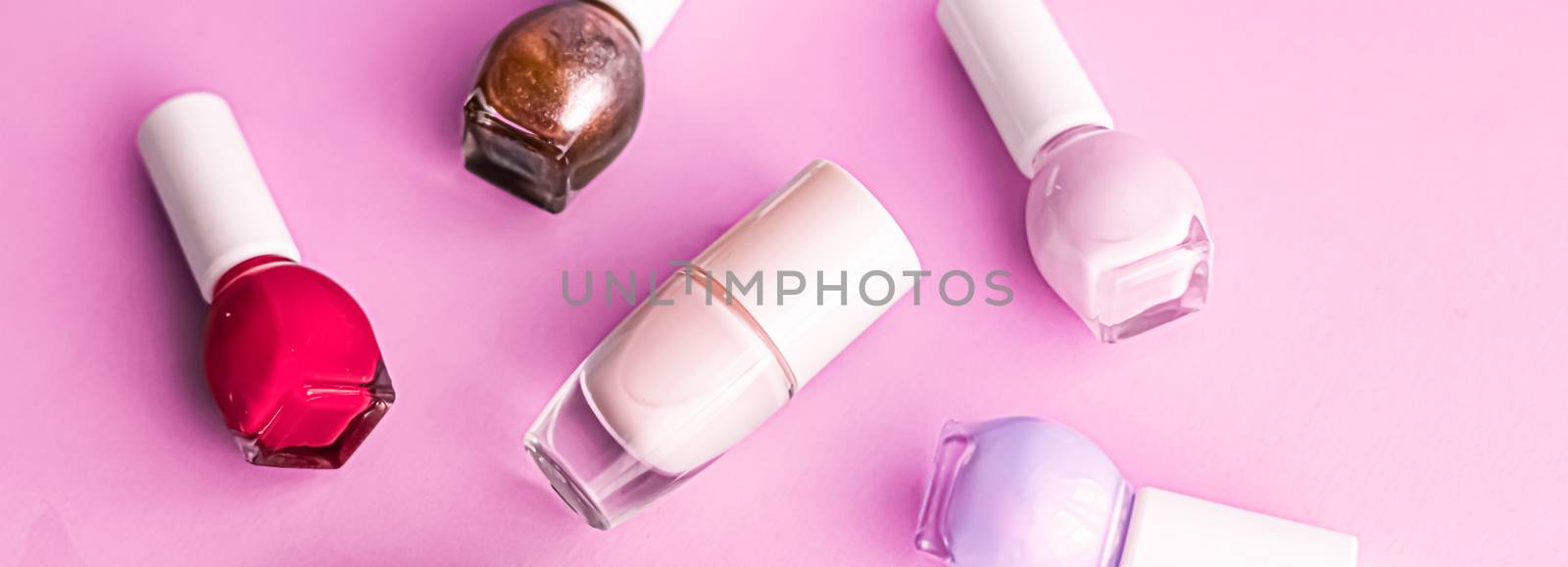 Nail polish bottles on pink background, beauty brand by Anneleven
