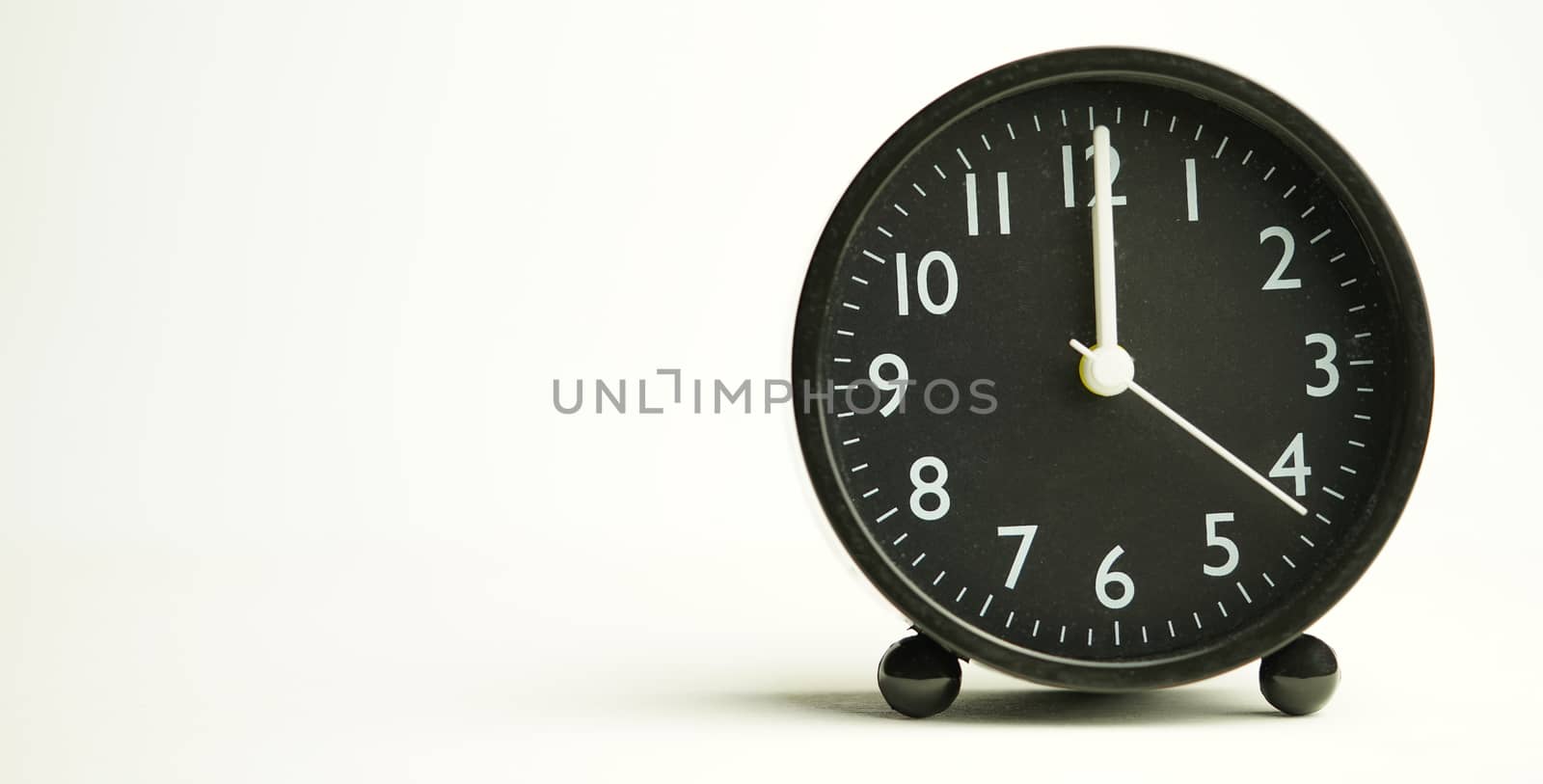 Decorative black alarm clock for noon separating white background with copy space.