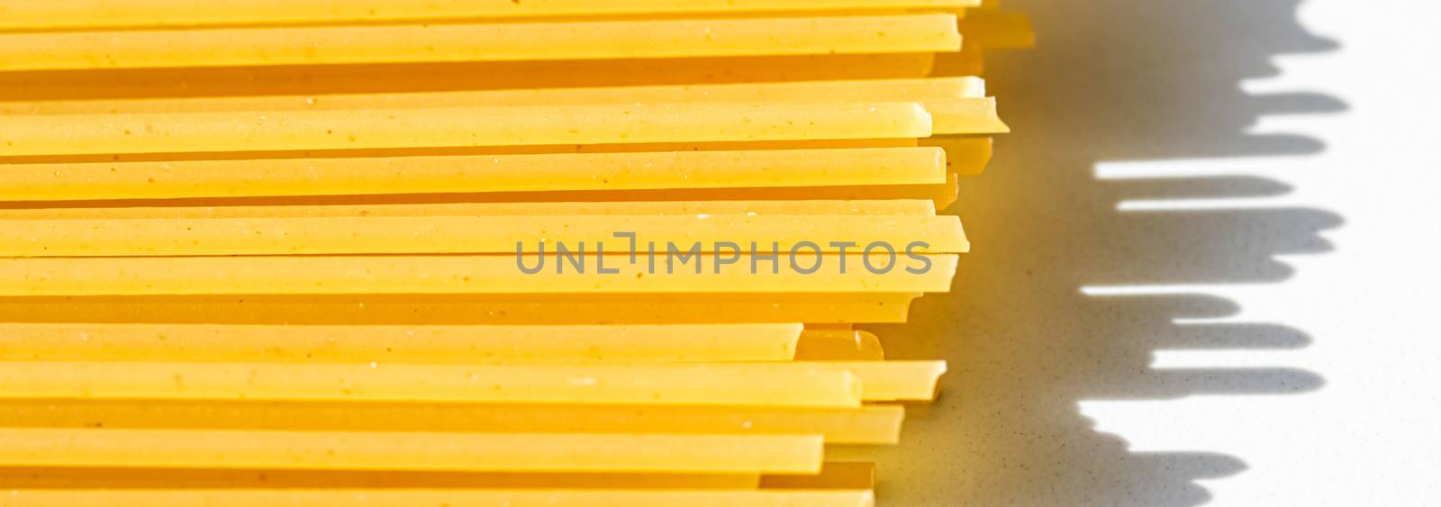 Uncooked whole grain spaghetti closeup, italian pasta as organic food ingredient, macro product and cook book recipe by Anneleven