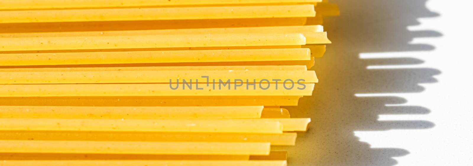 Uncooked whole grain spaghetti closeup, italian pasta as organic food ingredient, macro product and cook book recipes