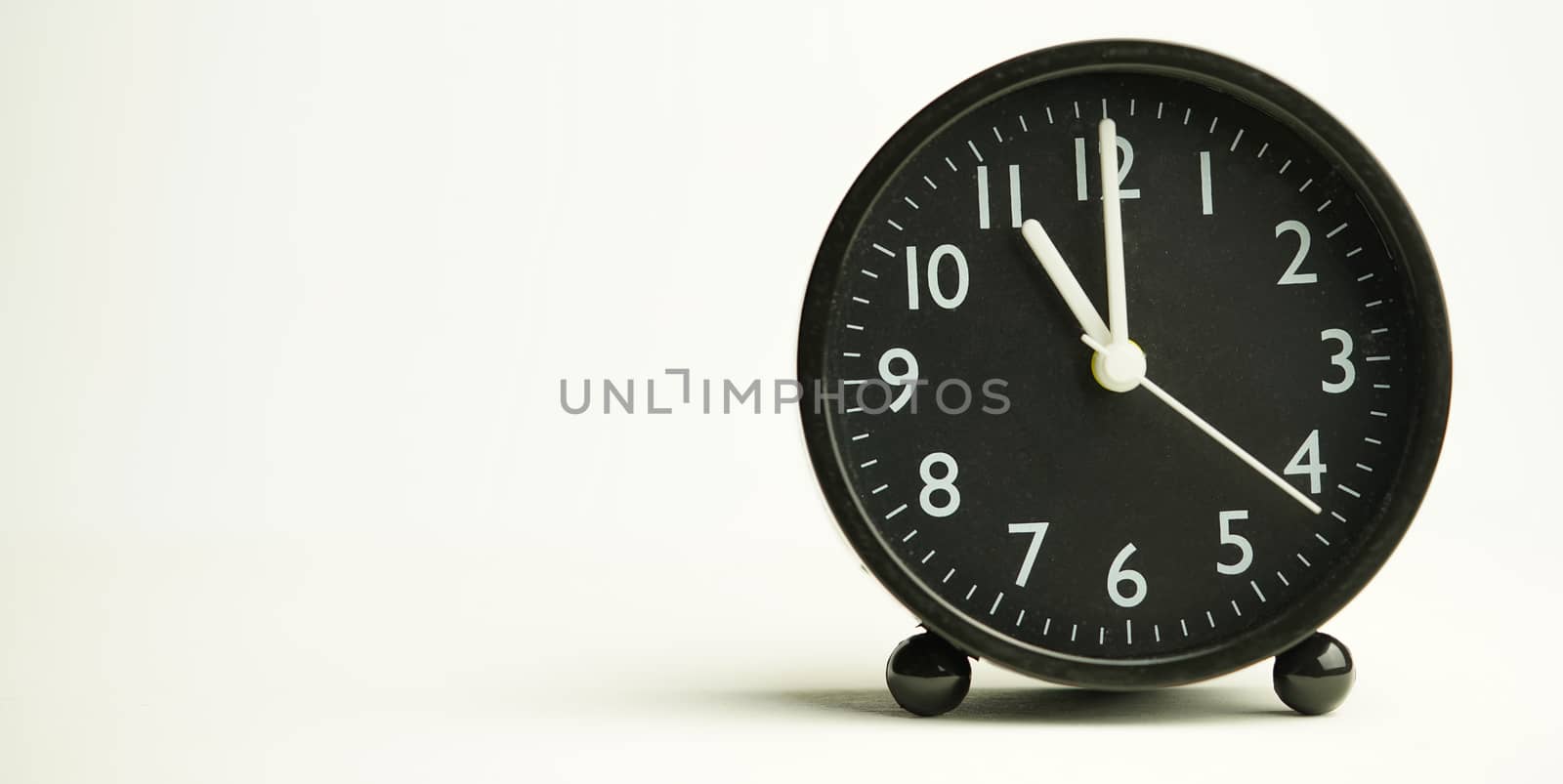 Decorative close-up black analog alarm clock for 10 o'clock isolated on white background with abstract copy space, start time of working day.