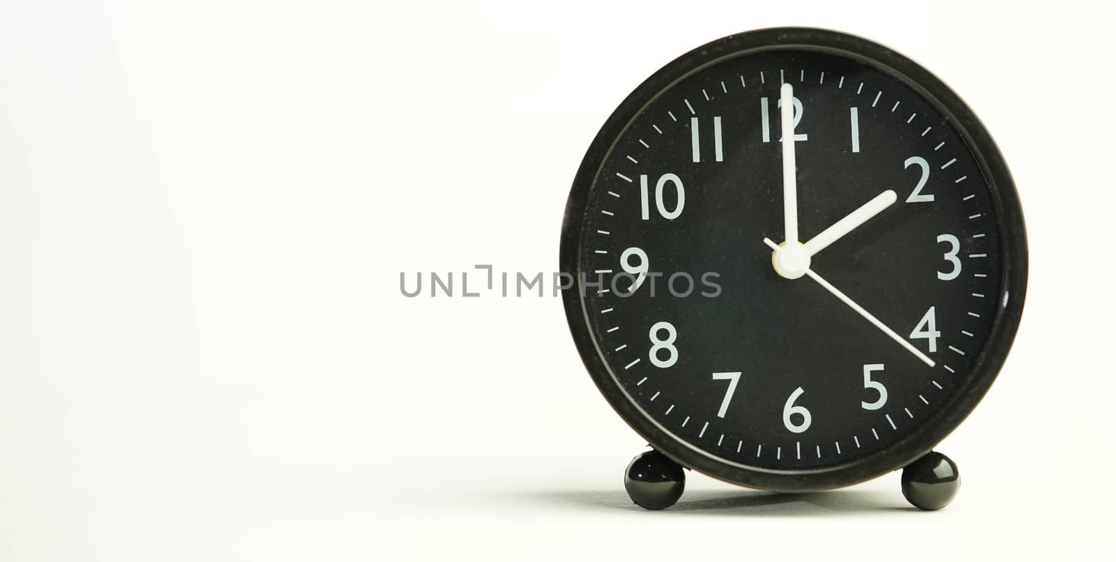 Decorative close-up black analog alarm clock for 2 o'clock, separate white background with copy space.