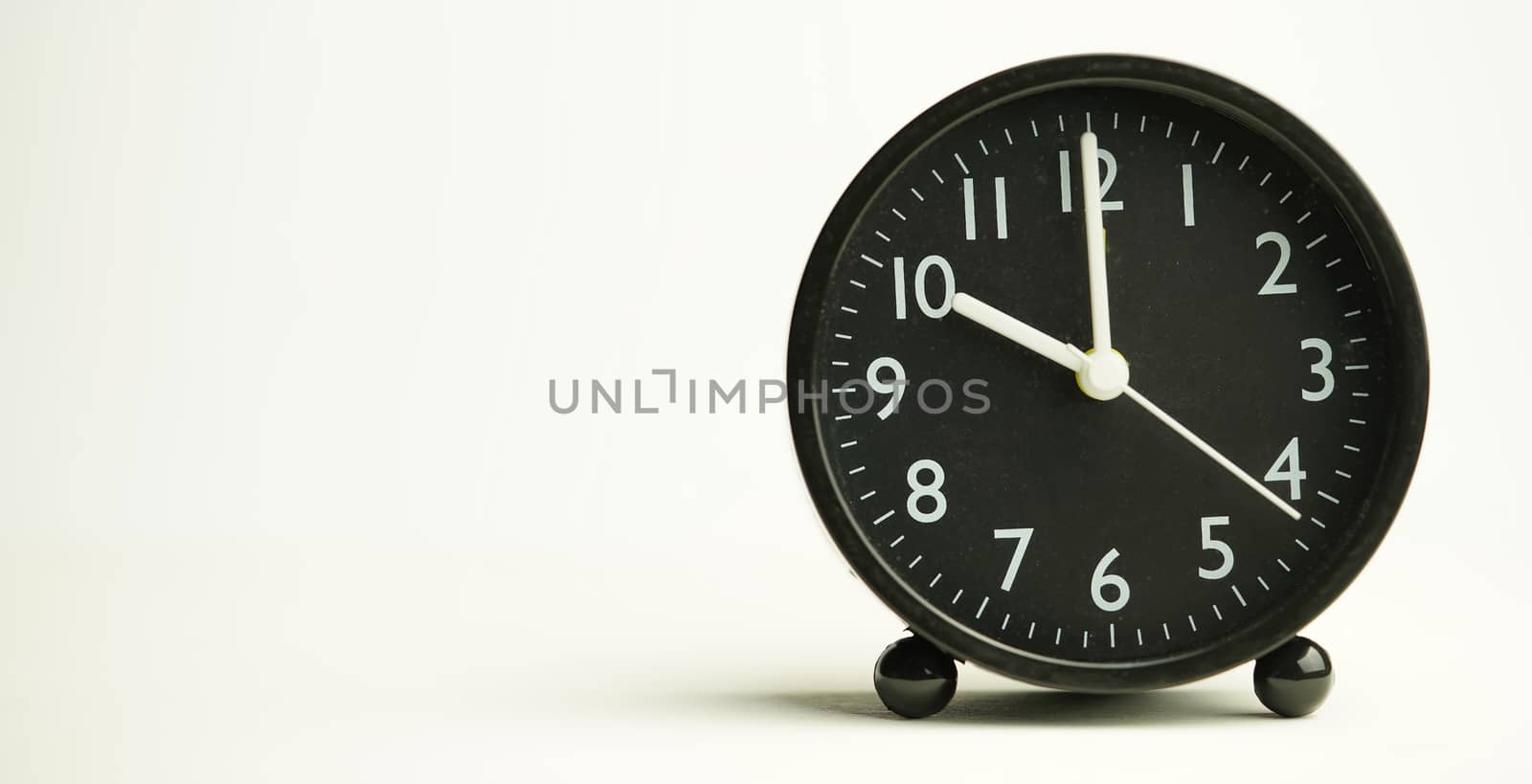 Decorative close-up black analog alarm clock for 10 o'clock isolated on white background with abstract copy space, start time of working day.