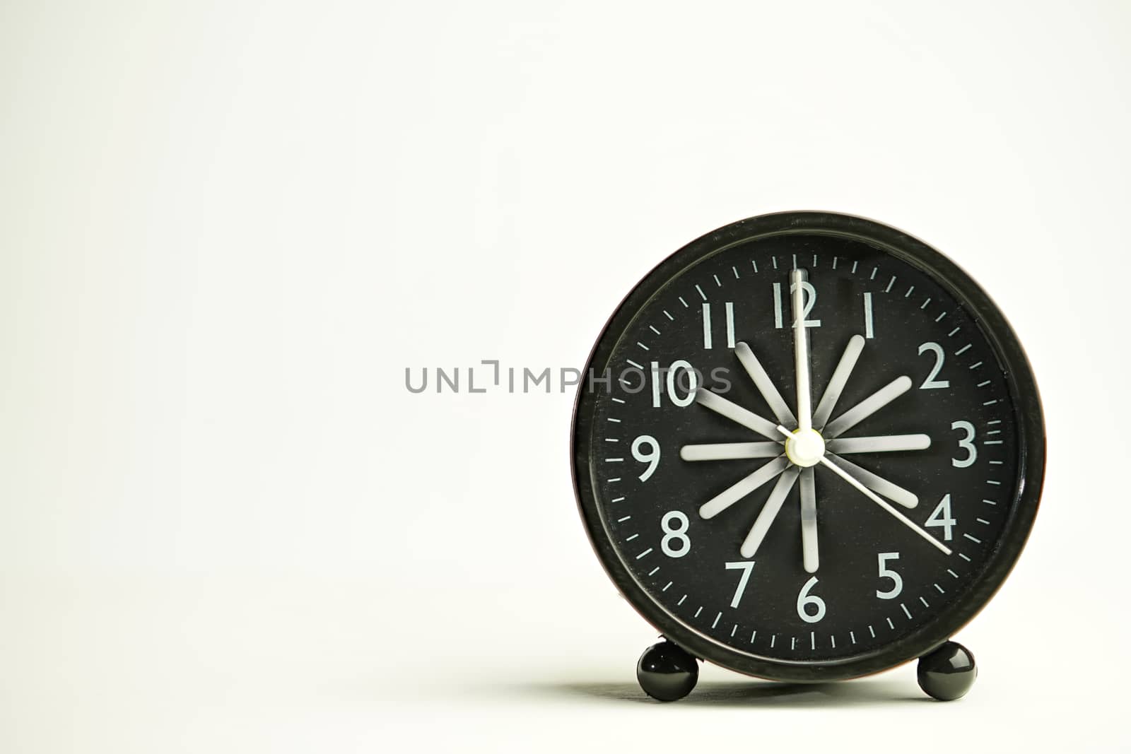 Abstract black analog alarm clock close-up inside being dusted island vintage style isolated white background with copy space. Use the Radius Blur technique.