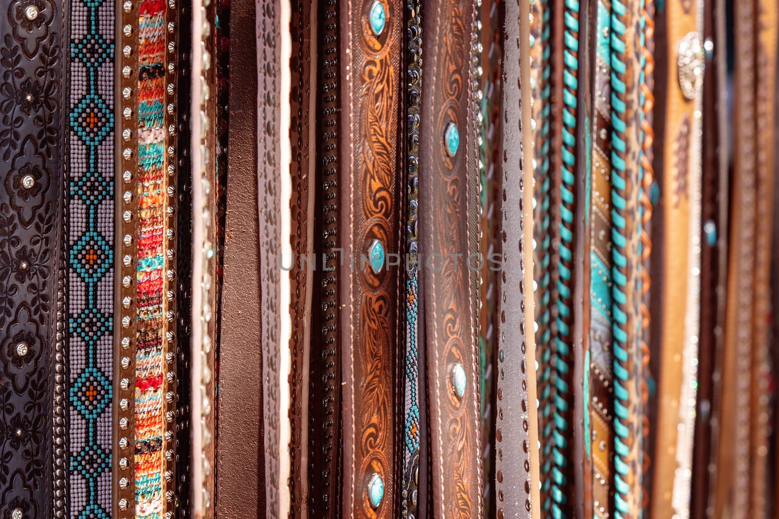 A group of women's country style leather belts for sale at a market stall