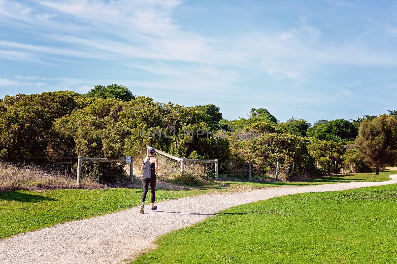 Girl jogging on a beach side track to get exercise in the great outdoors on a beautiful autumn day