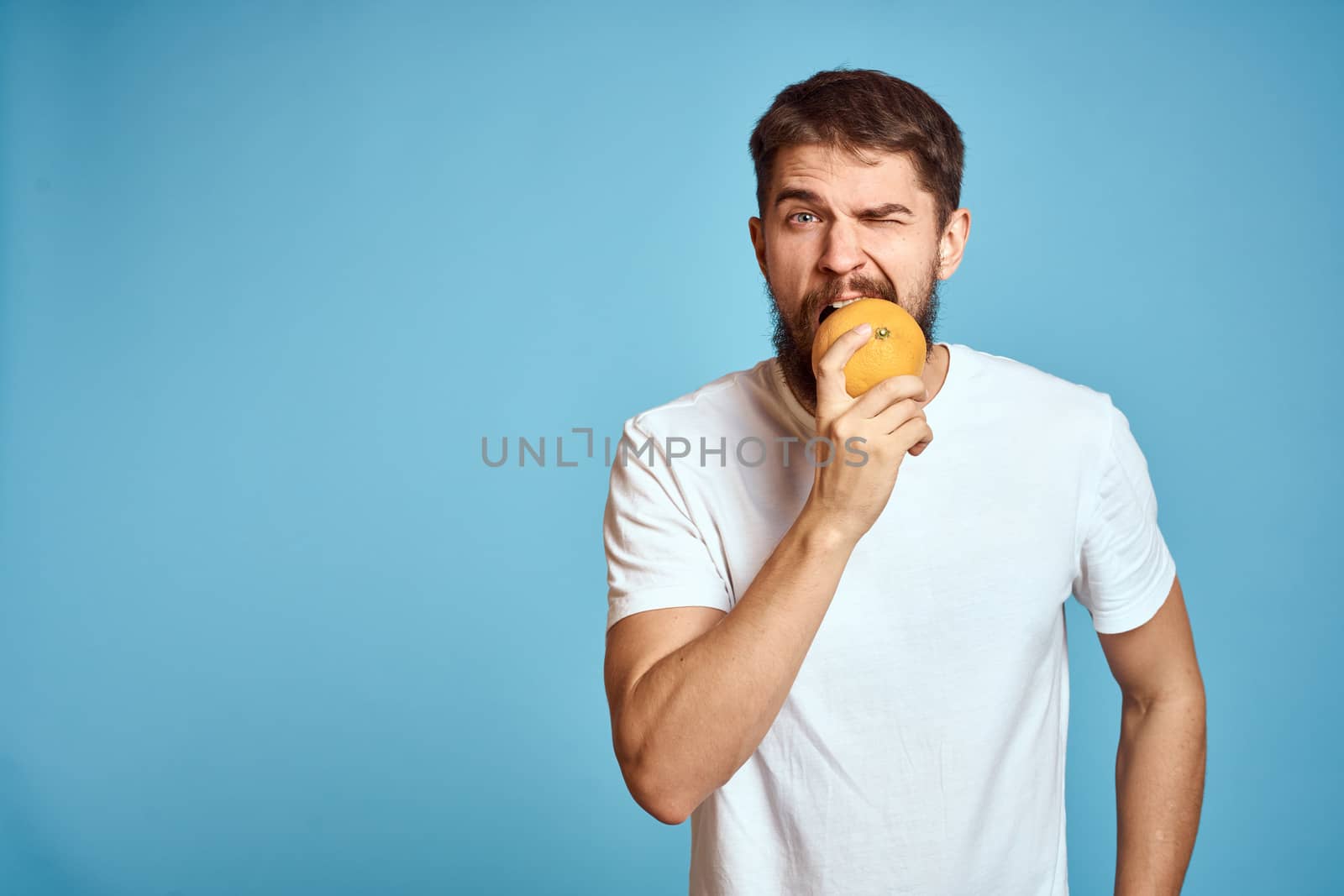 Bearded man with orange on blue background white t-shirt cropped view. High quality photo