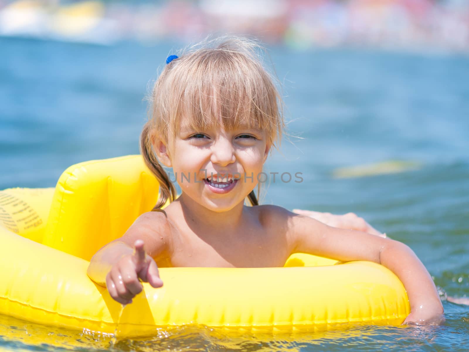 Portrait of little smiling girl with inflatable rubber circle in the sea in sunny day. Summer vacations concept.