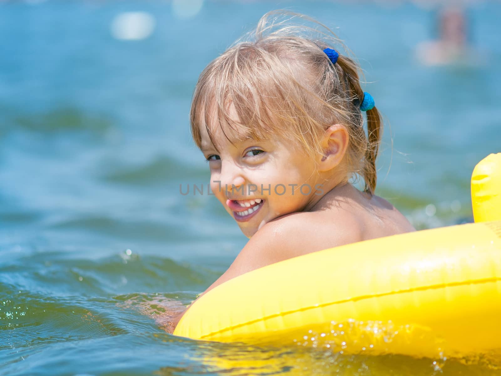 Portrait of little smiling girl with inflatable rubber circle in the sea in sunny day. Summer vacations concept.
