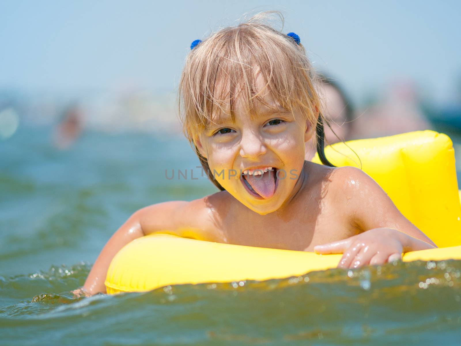 Portrait of little smiling girl with inflatable rubber circle in the sea in sunny day. Summer vacations concept.