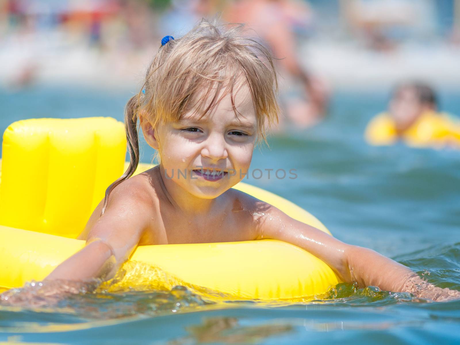 Portrait of little smiling girl with inflatable rubber circle in the sea in sunny day. Summer vacations concept.