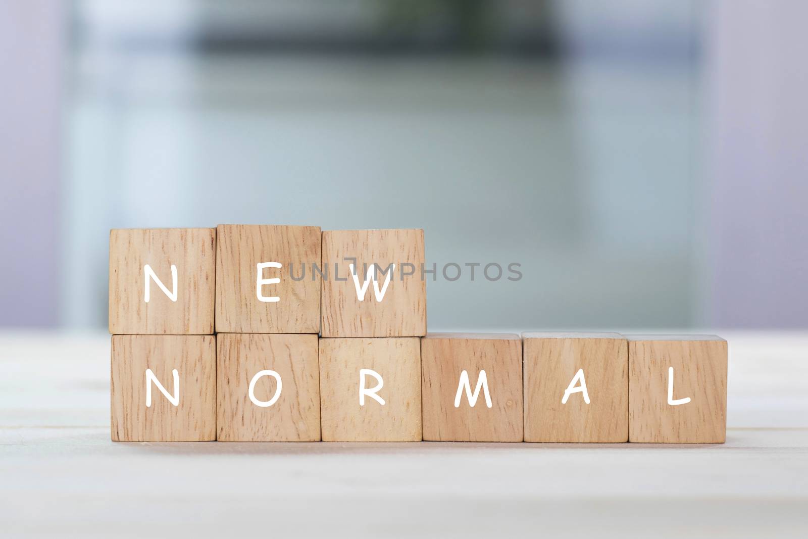 New normal on wooden cube with blurred background.