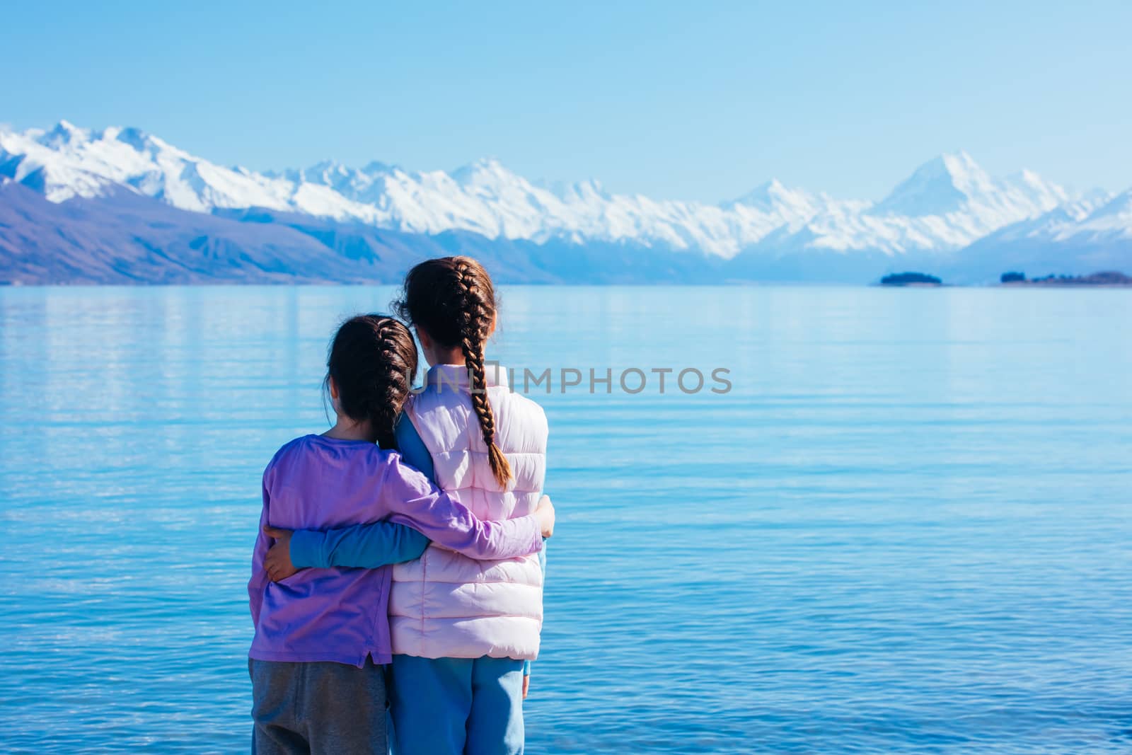 Young children look over Mt Cook and Lake Pukaki on a crystal clear spring morning in New Zealand