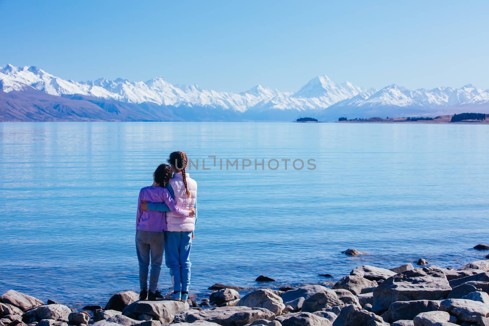 Young children look over Mt Cook and Lake Pukaki on a crystal clear spring morning in New Zealand