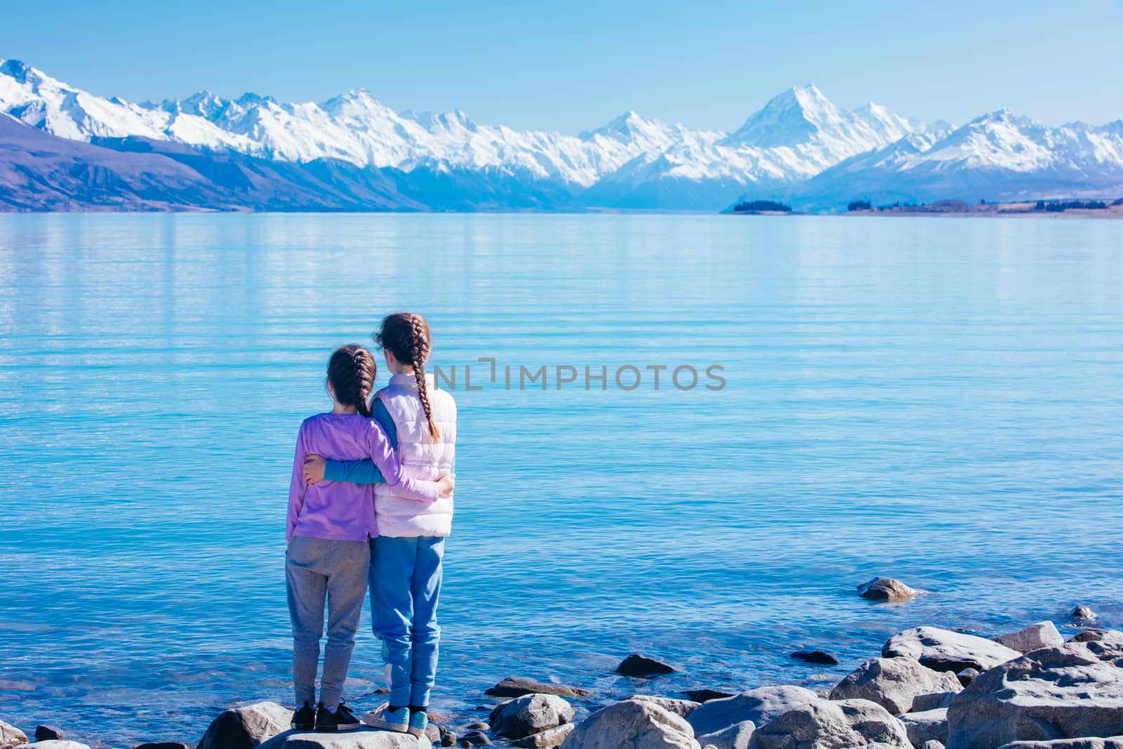 Young children look over Mt Cook and Lake Pukaki on a crystal clear spring morning in New Zealand