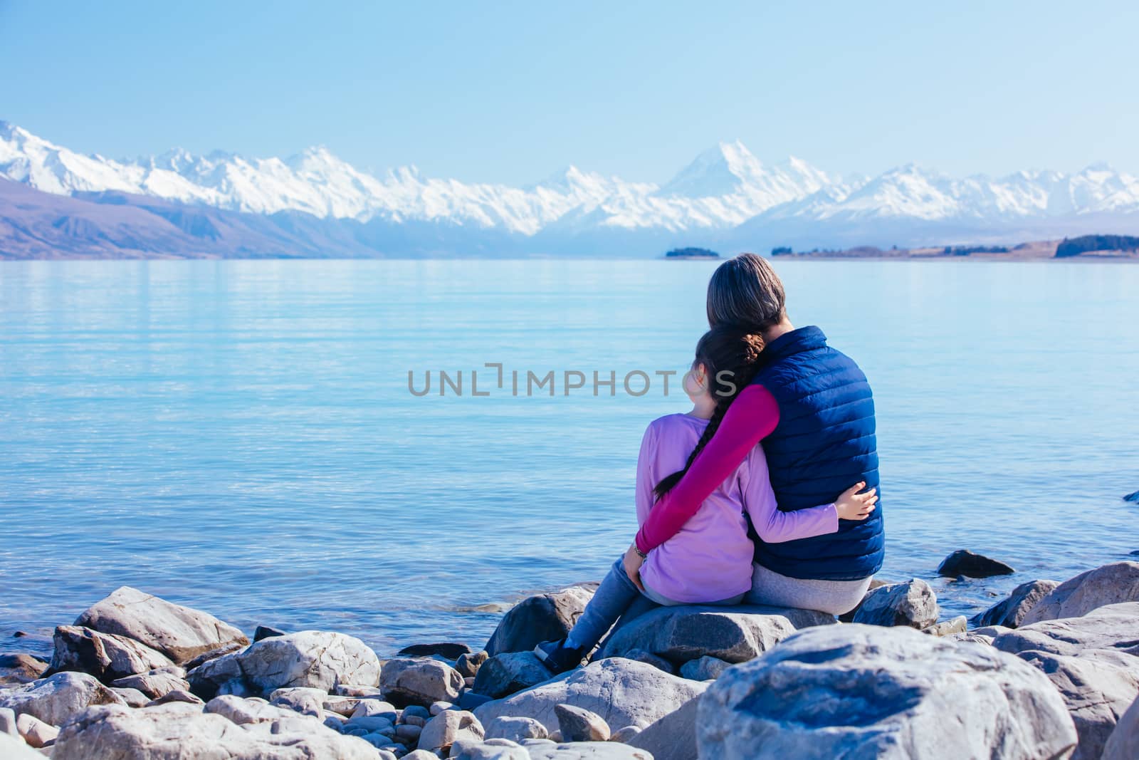 A young child and her Mum look over Mt Cook and Lake Pukaki on a crystal clear spring morning in New Zealand