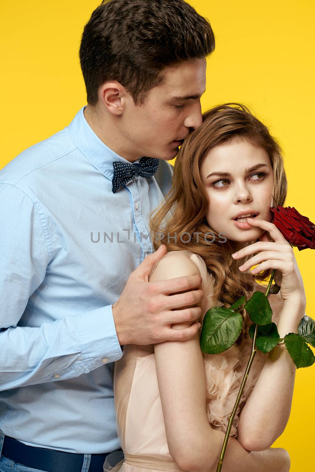 Enamored man and woman with red rose on yellow background cropped view close-up romance. High quality photo