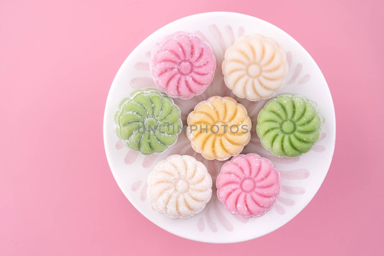 Colorful snow skin moon cake, sweet snowy mooncake, traditional savory dessert for Mid-Autumn Festival on pastel pale pink background, close up, lifestyle.