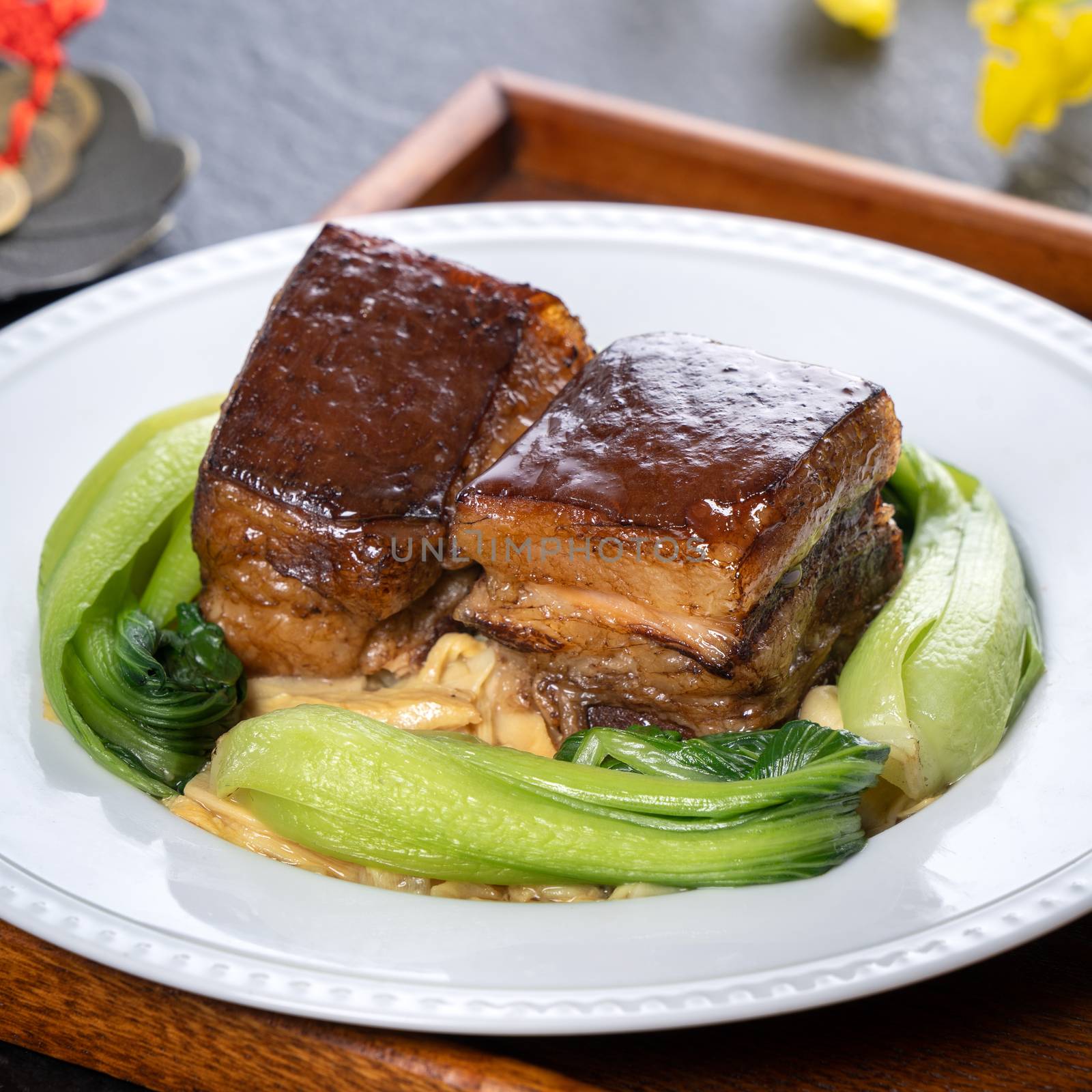 Dong Po Rou (Dongpo pork meat) in a beautiful plate with green broccoli vegetable, traditional festive food for Chinese new year cuisine meal, close up.