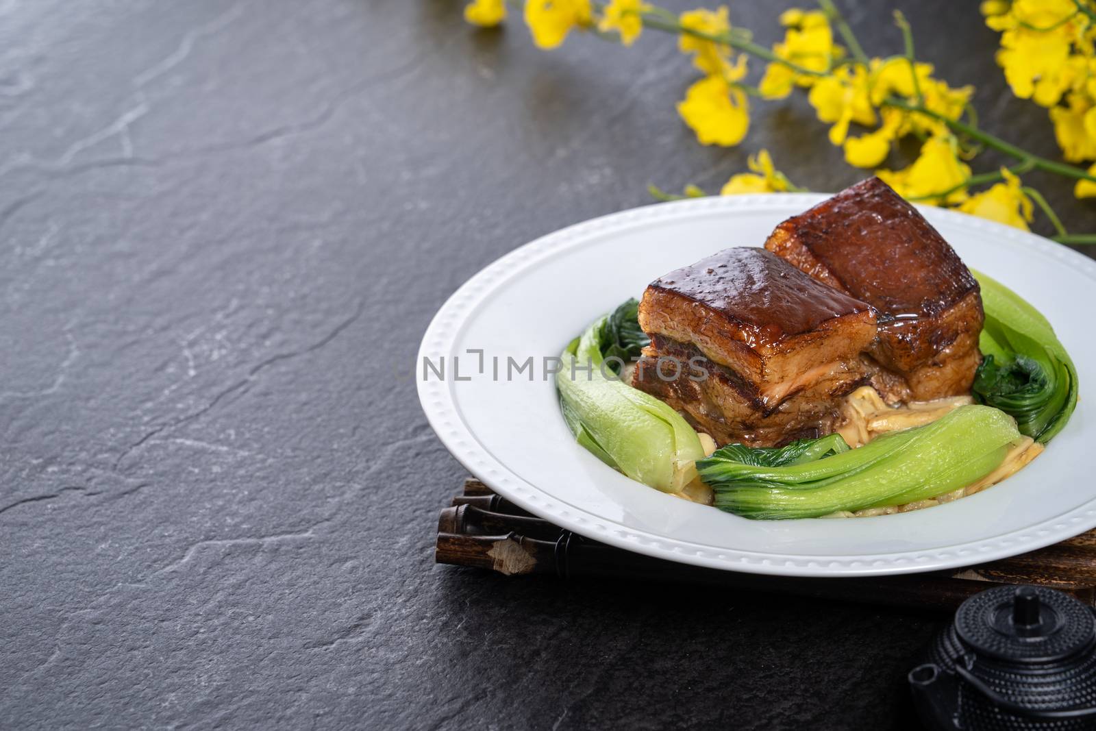 Dong Po Rou (Dongpo pork meat) in a beautiful plate with green broccoli vegetable, traditional festive food for Chinese new year cuisine meal, close up.