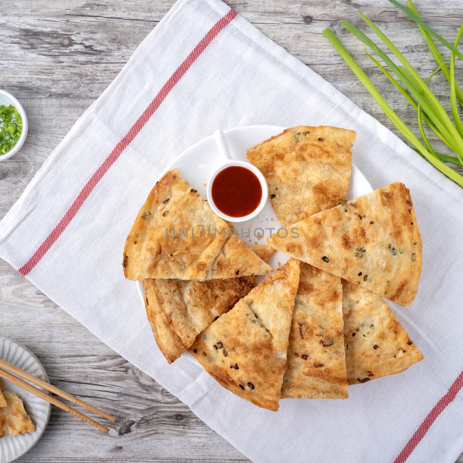 Taiwanese food - delicious flaky scallion pie pancakes on bright wooden table background, traditional snack in Taiwan, top view.