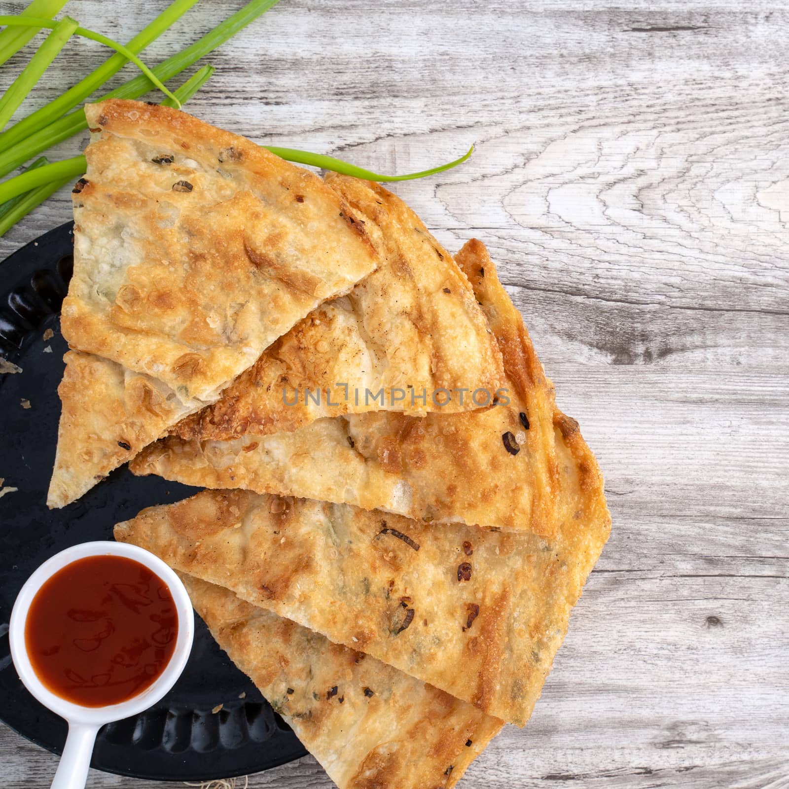 Taiwanese food - delicious flaky scallion pie pancakes on bright wooden table background, traditional snack in Taiwan, top view.