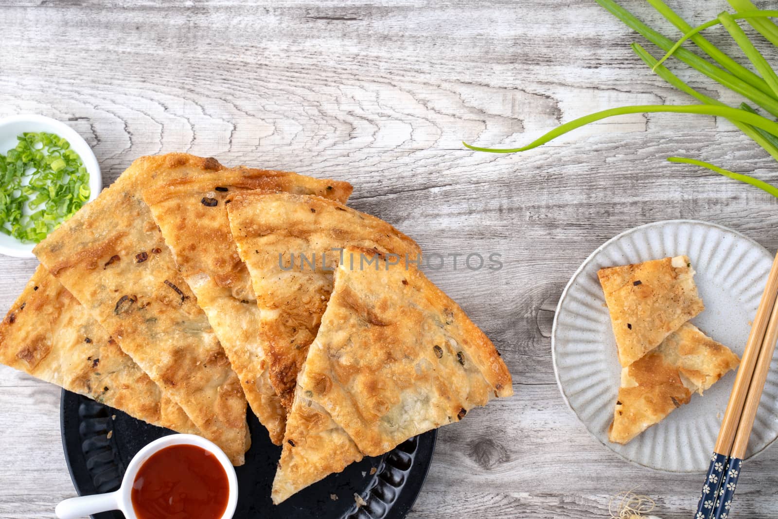 Taiwanese food - delicious flaky scallion pie pancakes on bright wooden table background, traditional snack in Taiwan, top view.