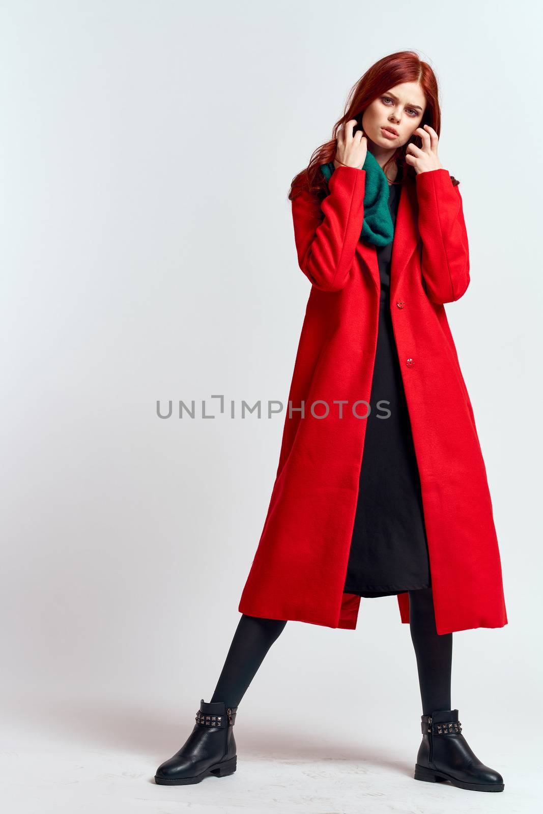 emotional woman in a red coat and with a hat in full growth on a light background black boots pose model. High quality photo