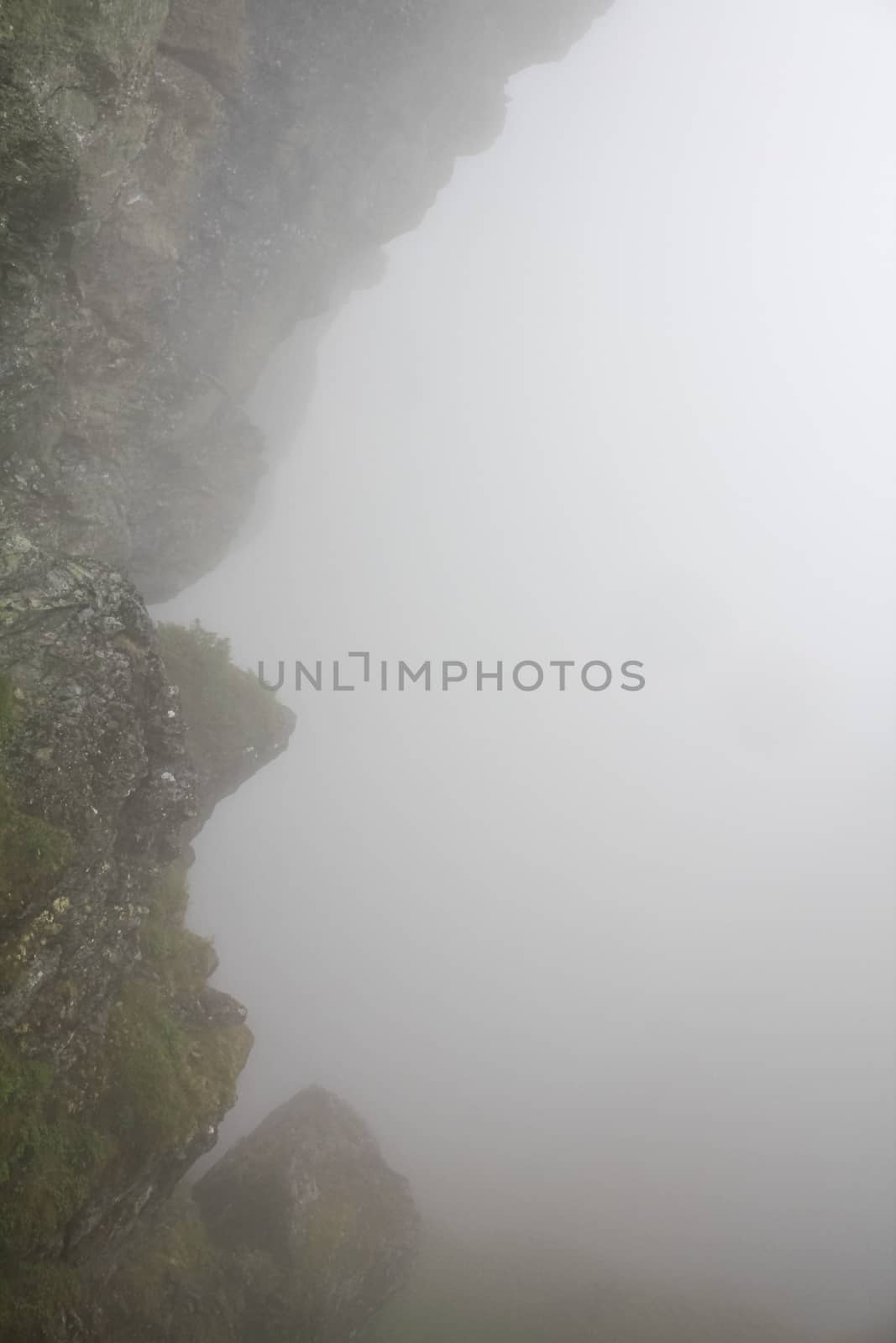 Fog, clouds, rocks and cliffs on Veslehødn Veslehorn mountain, Norway. by Arkadij