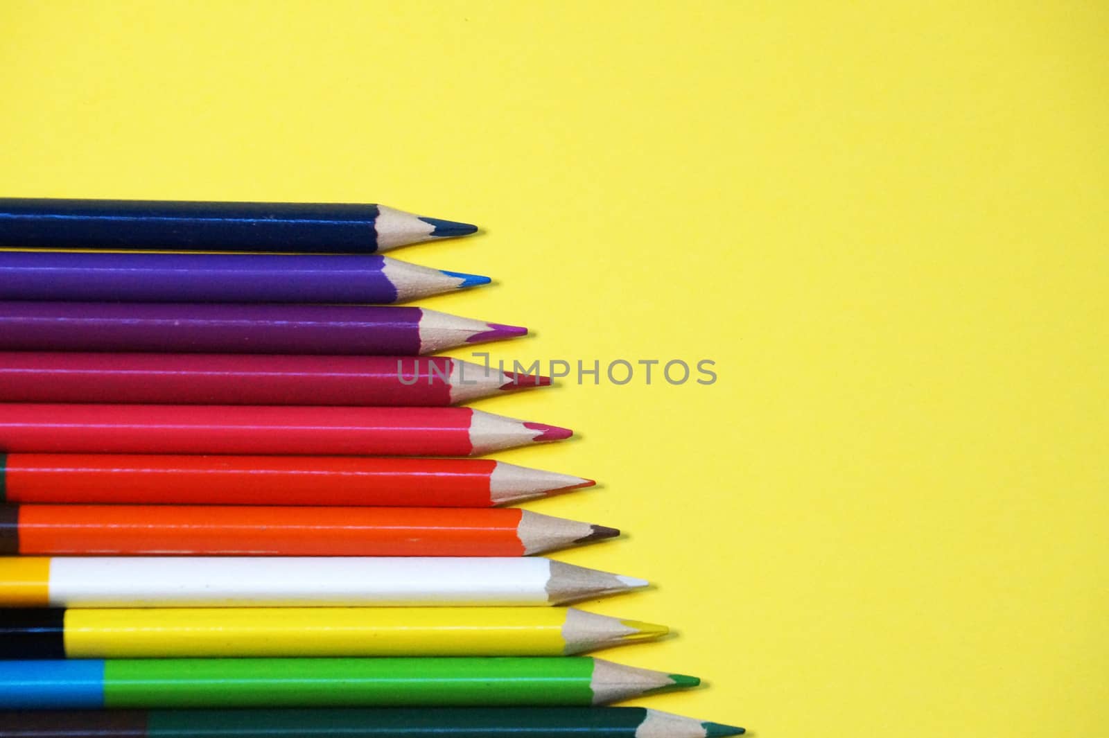 multicolored pencils on a yellow background close up