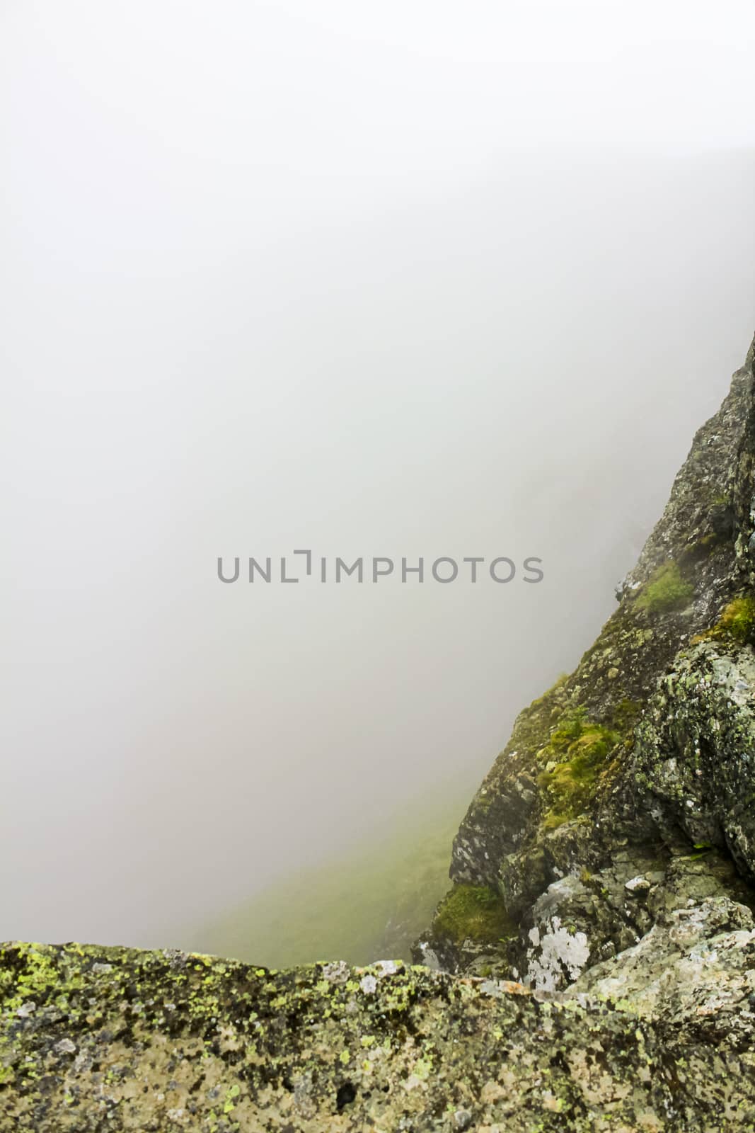 Fog, clouds, rocks and cliffs on Veslehødn Veslehorn mountain, Norway. by Arkadij