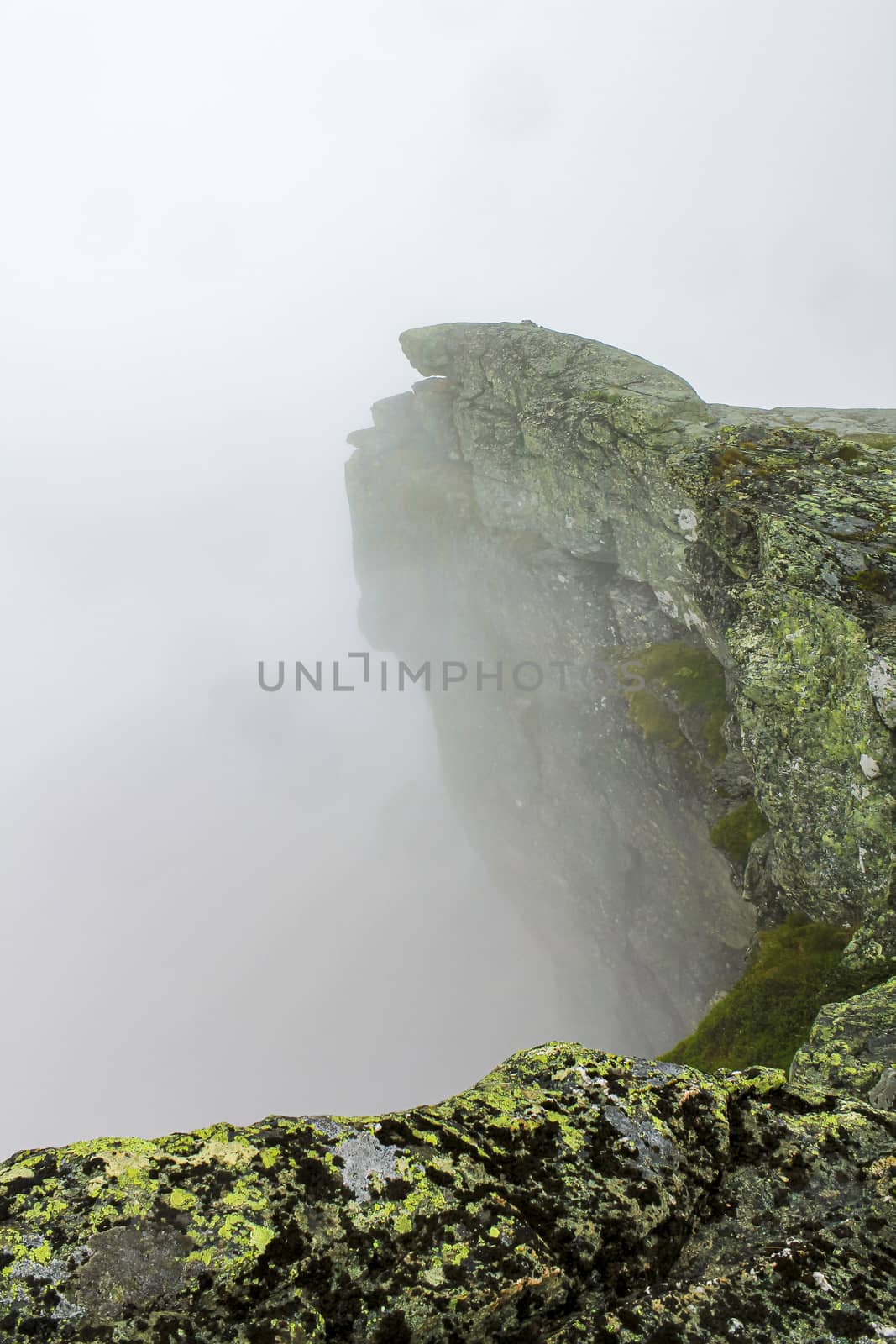 Fog, clouds, rocks and cliffs on Veslehødn Veslehorn mountain, Norway. by Arkadij