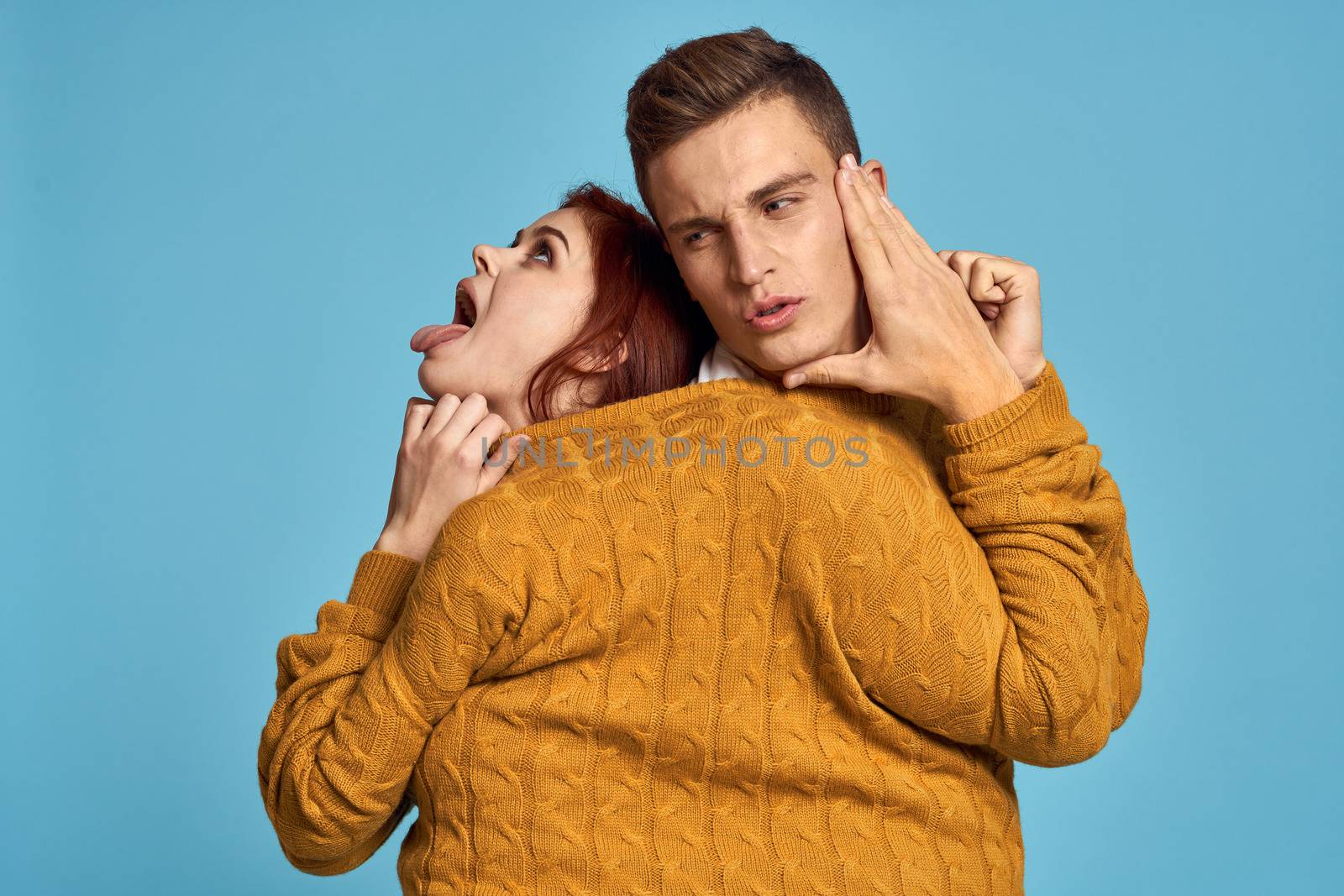 couple in yellow sweater posing against blue background cropped view by SHOTPRIME