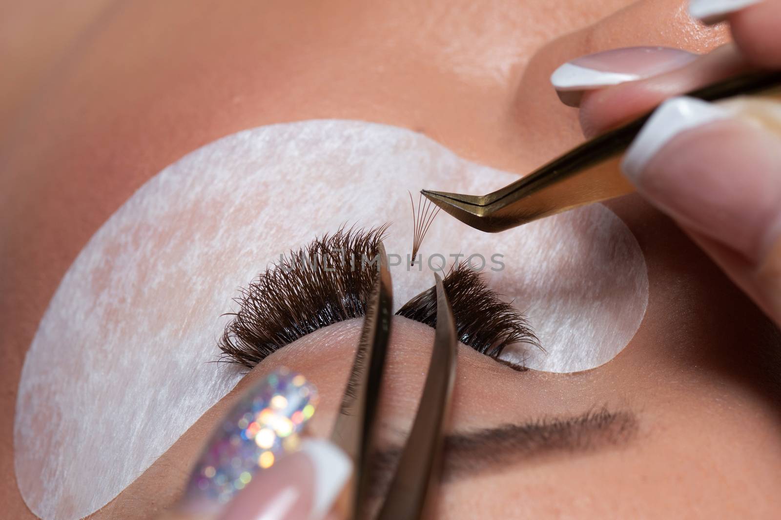 Eyelash Extension Procedure. Woman Eye with Long Eyelashes. Lashes. Close up tweezers, macro, selective focus