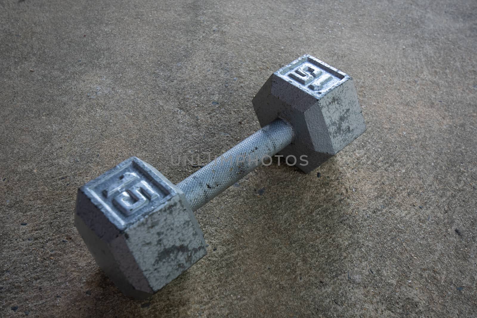 A Silver Fifteen Pound Dumbbell on Concrete by bju12290