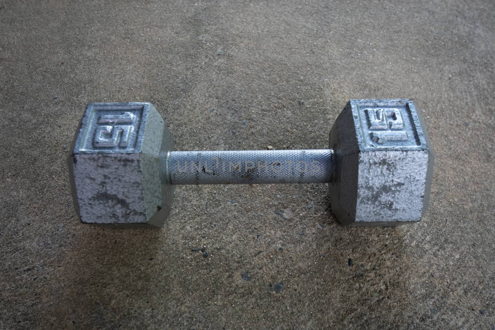 An Old Silver Fifteen Pound Weight on Concrete