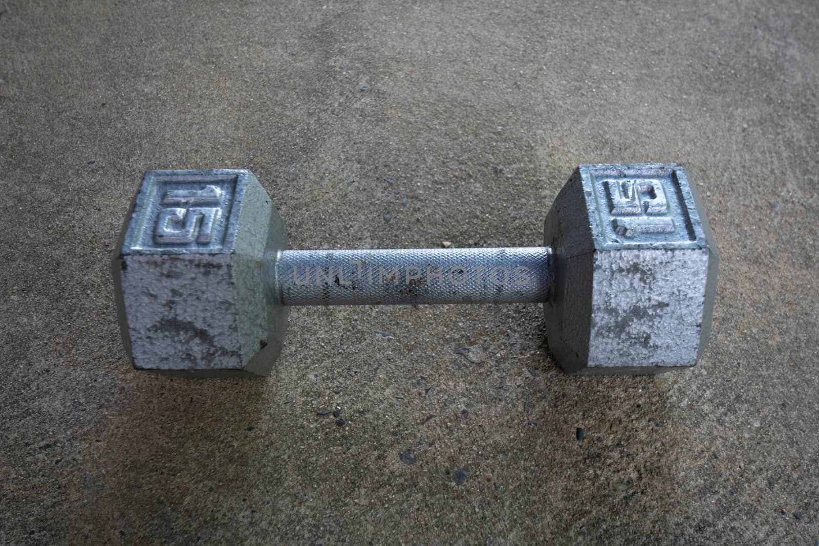 A Silver Fifteen Pound Dumbbell on Concrete by bju12290