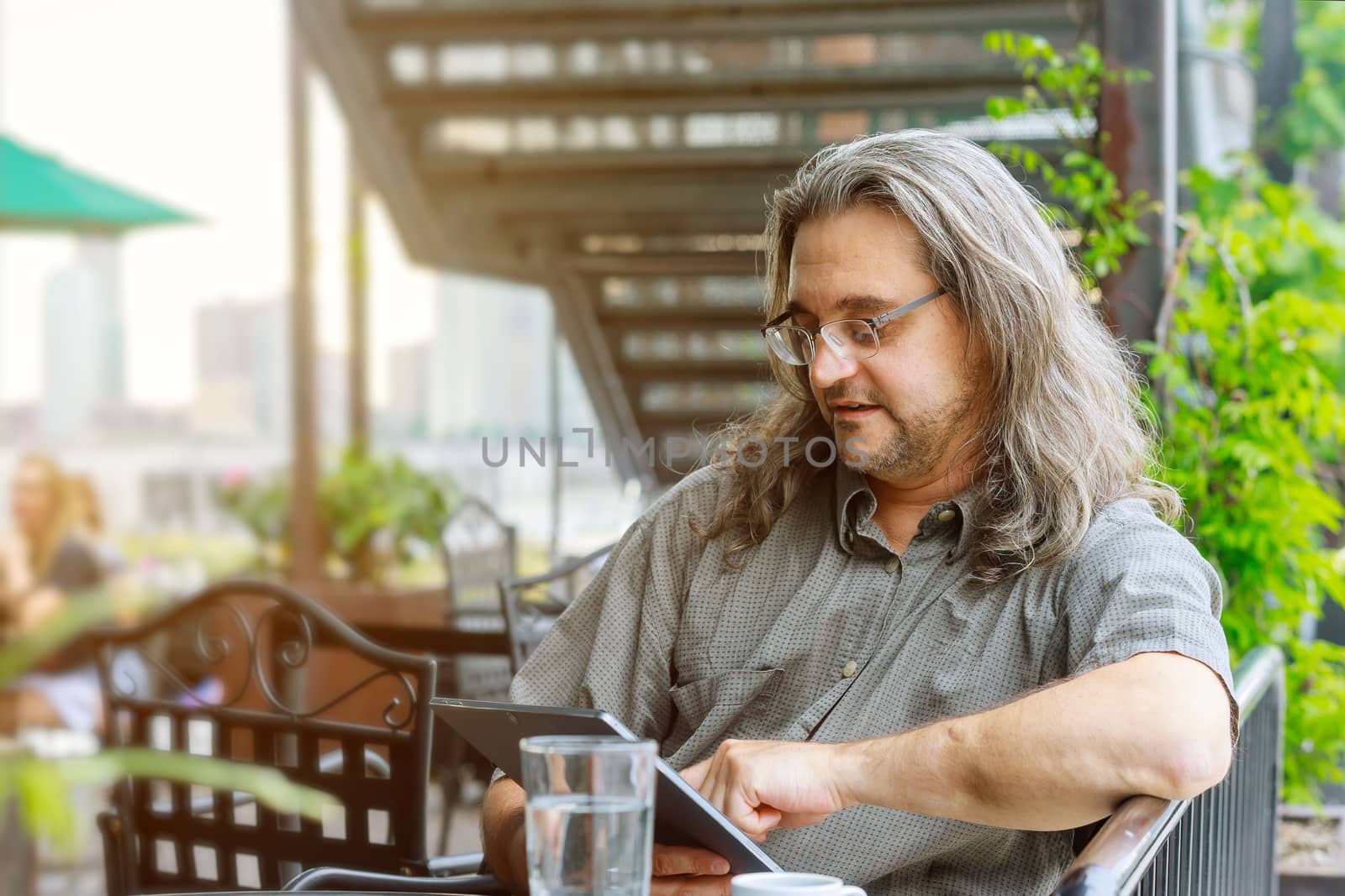 Man wearing glasses and working with touchpad while sitting on the coffee shop