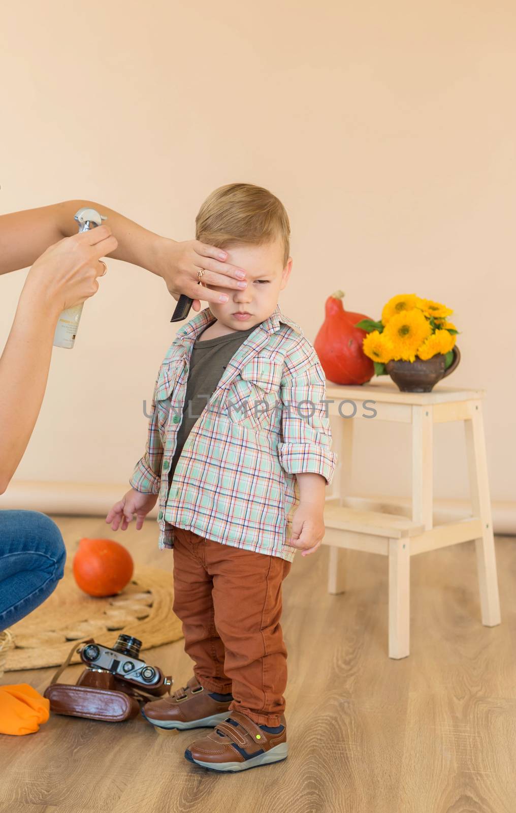 Mom combing her little son in the studio before a photo session