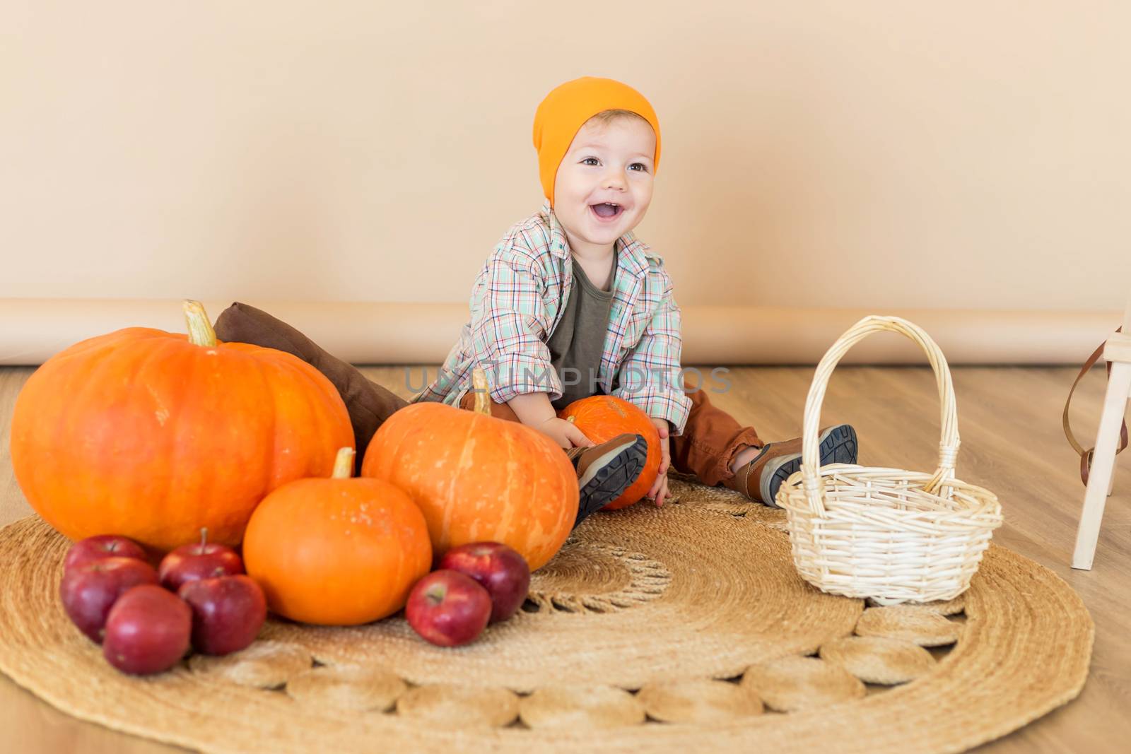 A little boy sits among pumpkins with a basket of ducklings.