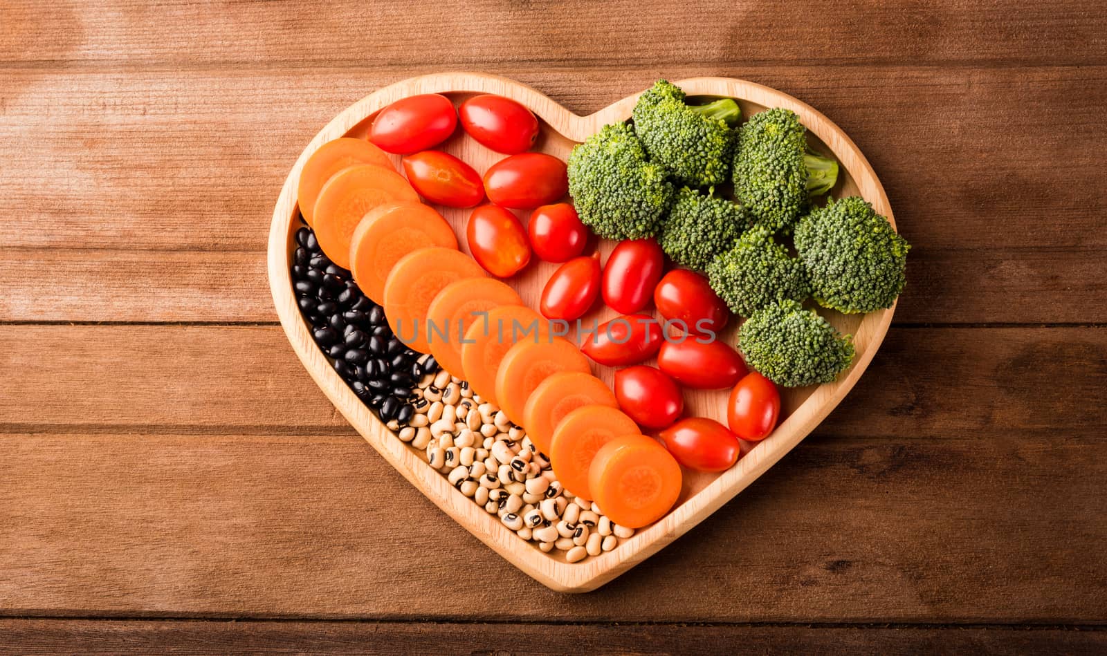 Top view of fresh organic fruits and vegetables in heart plate wood (carrot, Broccoli, tomato) on wooden table, Healthy lifestyle diet food concept