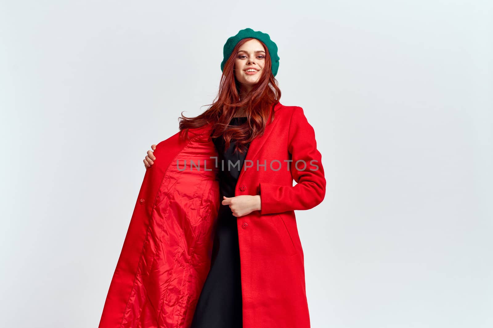 Portrait of a woman in a red coat and in a green hat dark clothes light background model cropped view. High quality photo