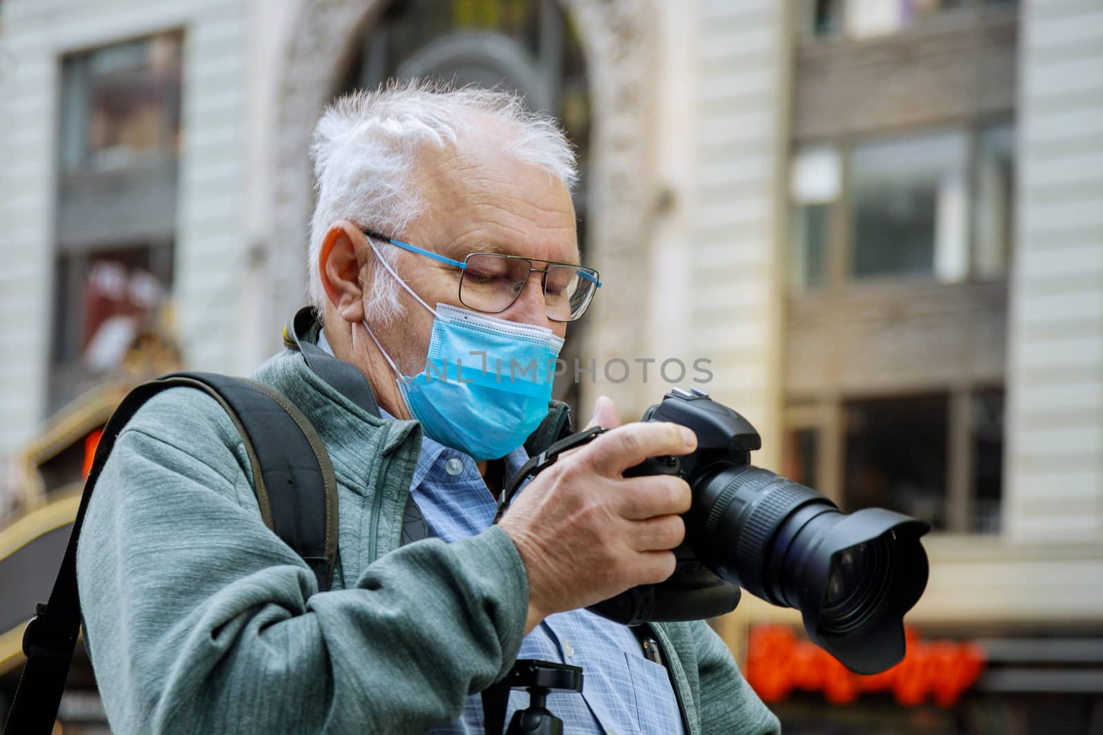 Man with mask taking a picture by the in Manhattan, New York skyscraper